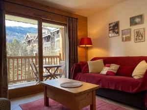 d'un salon avec un canapé rouge et un balcon. dans l'établissement Appartement Samoëns, 3 pièces, 6 personnes - FR-1-624-23, à Samoëns