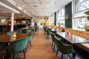 un restaurante con mesas de madera y sillas verdes en Hotel Royal en Noordwijk