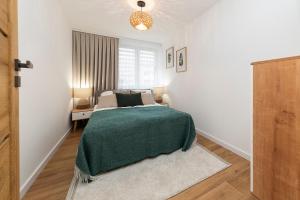 une chambre avec un lit avec une couverture verte dans l'établissement Mieszkanie Jagiellońska Kładka przy Morzu i PKP, à Kołobrzeg
