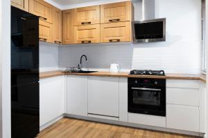 une cuisine avec des armoires blanches et un appareil noir dans l'établissement Mieszkanie Jagiellońska Kładka przy Morzu i PKP, à Kołobrzeg
