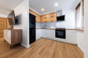 une cuisine avec des armoires blanches et des appareils noirs dans l'établissement Mieszkanie Jagiellońska Kładka przy Morzu i PKP, à Kołobrzeg 9 autres photos