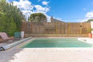 a swimming pool in a backyard with a wooden fence at Villa - Chez Dominique in Manosque