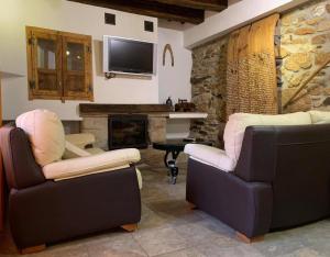 a living room with two chairs and a fireplace at Casa Rural La Vertedera 3 in Villar de Ciervo