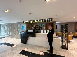 a man in a suit standing in front of a bar at Turk Inn 2017 Otel in Ankara