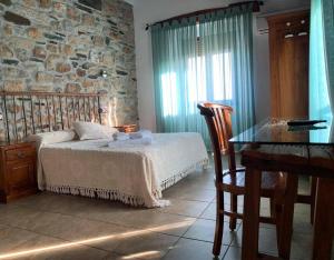 1 dormitorio con cama, mesa y pared de piedra en Casa Rural La Vertedera 3, en Villar de Ciervo