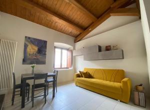 a living room with a yellow couch and a table at Dimore Il Duomo in LʼAquila