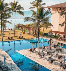 a large swimming pool with palm trees and a hotel at Polinésia resort em Porto de Galinhas Muro Alto - Acesso Total ao Samoa Beach Resort in Porto De Galinhas