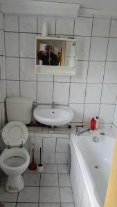 un hombre tomando una foto de un baño con aseo y lavabo en Dreiseithof bei Luckenwalde, en Schönefeld