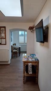 a living room with a table and a television on a wall at Zimmer am See in Fußach