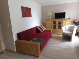 a living room with a red couch and a chair at Hof Gerbert in Halenbeck