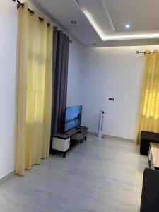 a living room with yellow curtains and a flat screen tv at Luxueuse cité in Bodjo