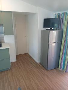 a small kitchen with a refrigerator and a television at Camping du Lac in Foix