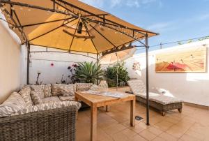 a patio with a couch and a table and an umbrella at Villa Christiane in Ses Salines