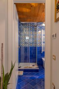 a blue tiled bathroom with a shower and a toilet at The House of Flowers in Vietri