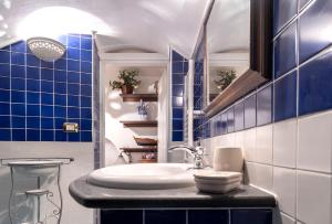baño con lavabo y pared de azulejos azules en The House of Flowers, en Vietri