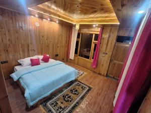 - une chambre avec un grand lit et des oreillers roses dans l'établissement BESTIE WOODEN COTTAGE JIBHI, à Jibhi