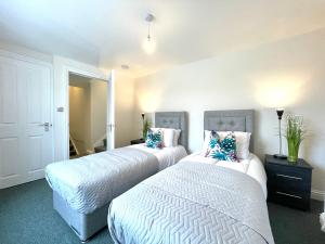 two beds in a bedroom with white sheets and blue pillows at Renovated 2 Bedroom Apartment With 2 Bathrooms in Bristol