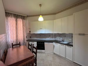 a kitchen with white cabinets and a table and a sink at Appartamento La Nautica in Portoferraio