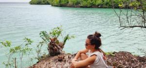 a woman sitting on a rock near a body of water at Camping club apwisindo chandra in Kema