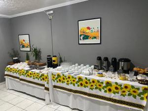 a table with sunflowers and cups on it at Hotel Jabaquara Imiggrantes - By UP Hotel - Metro Jabaquara - 2KM Expo São Paulo in Sao Paulo