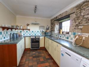 a kitchen with blue and white tiles on the wall at The Coach House in Haroldston West