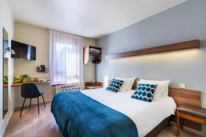 een slaapkamer met een groot bed en een blauwe deken bij Hotel Restaurant Le Sainte Mere in Sainte-Mère-Église