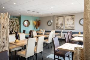 a dining room with wooden tables and chairs at Logis Hôtel Restaurant Le Sainte Mère in Sainte-Mère-Église