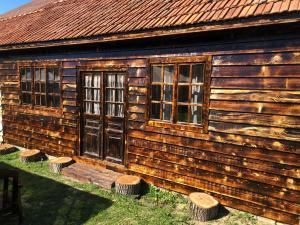 una vieja cabaña de madera con ventanas y taburetes delante en Old Court en Curtea de Argeş