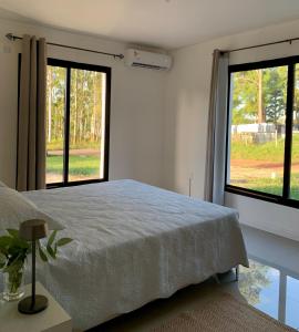 1 dormitorio con 1 cama y 2 ventanas grandes en CASA moderna en la floresta a 5 minutos de Punta Ballena, en Maldonado
