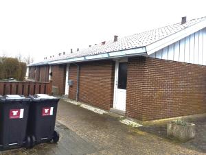 een bakstenen gebouw met twee vuilnisbakken ervoor. bij (id110) Grønlandsparken 56. G in Esbjerg