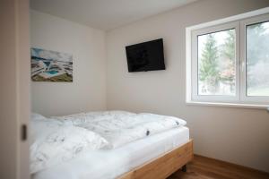 a white bedroom with a bed and a window at Premium Apartments Monterra in Petschnitzen