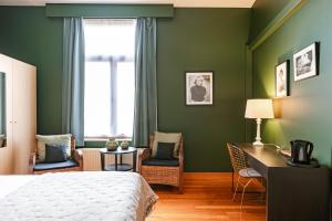 a bedroom with green walls and a bed and a desk at Hotel Malleberg in Bruges