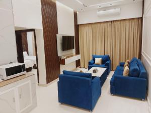 a living room with two blue chairs and a tv at Mabahj Garnatha Hotel Apartments in Sohar