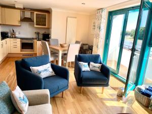 a living room with two blue chairs and a kitchen at Crabshell Quay waterfront living in Kingsbridge in Kingsbridge
