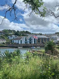 una casa con una bandera frente a un cuerpo de agua en Crabshell Quay waterfront living in Kingsbridge, en Kingsbridge
