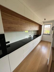 a kitchen with white cabinets and wooden floors at Dunajec Home 