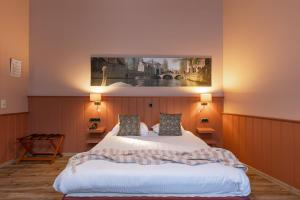a bedroom with a large white bed with two pillows at Hotel Malleberg in Bruges