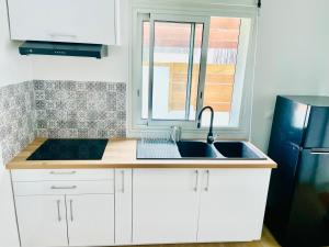 a kitchen with a sink and a black refrigerator at Villa des Ajoncs Ermitage les Bains-150m du Lagon in L'Ermitage-Les-Bains +8 photos