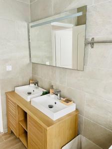a bathroom with two sinks and a mirror at Villa des Ajoncs Ermitage les Bains-150m du Lagon in L'Ermitage-Les-Bains