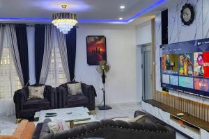 sala de estar con 2 sofás y TV de pantalla plana en MeTime Residence Enugu, en Enugu