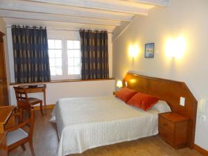 a bedroom with a bed and a desk and a window at Hotel Eskualduna Chez Katina in Saint-Martin-dʼArrossa