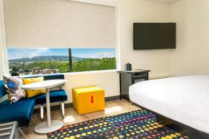 a hotel room with a bed and a desk and a window at Aloft Knoxville West in Knoxville