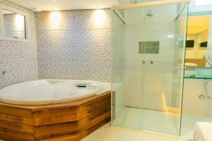 a bathroom with a tub and a glass shower at Bluh Motel in Curitiba