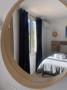 AUBERGE DES PINS في باندول: غرفة نوم مع مرآة دائرية كبيرة على الحائط