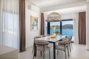 een eetkamer met een tafel en stoelen en een groot raam bij Villa Maris, 10m from beach, infinity pool in Kučište
