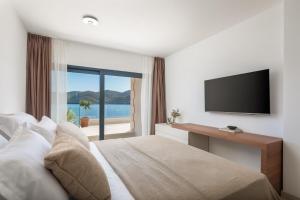 een hotelkamer met een bed en een televisie bij Villa Maris, 10m from beach, infinity pool in Kučište +70 foto's