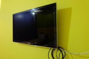 B&B House & Hostel في مينْغكرابي: تلفزيون بشاشة مسطحة على جدار أخضر