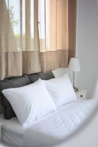 a bed with white sheets and a window at Daphne's studio 1 in Skiathos