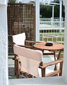 a porch with a wooden table and two white chairs at Daphne's studio 1 in Skiathos Town