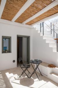 a white house with a table and stairs at aníko suites White Alley in Mýkonos City